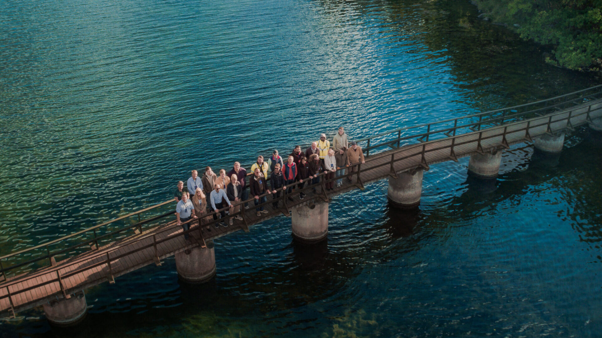 A group of people standing on a bridge in the water.