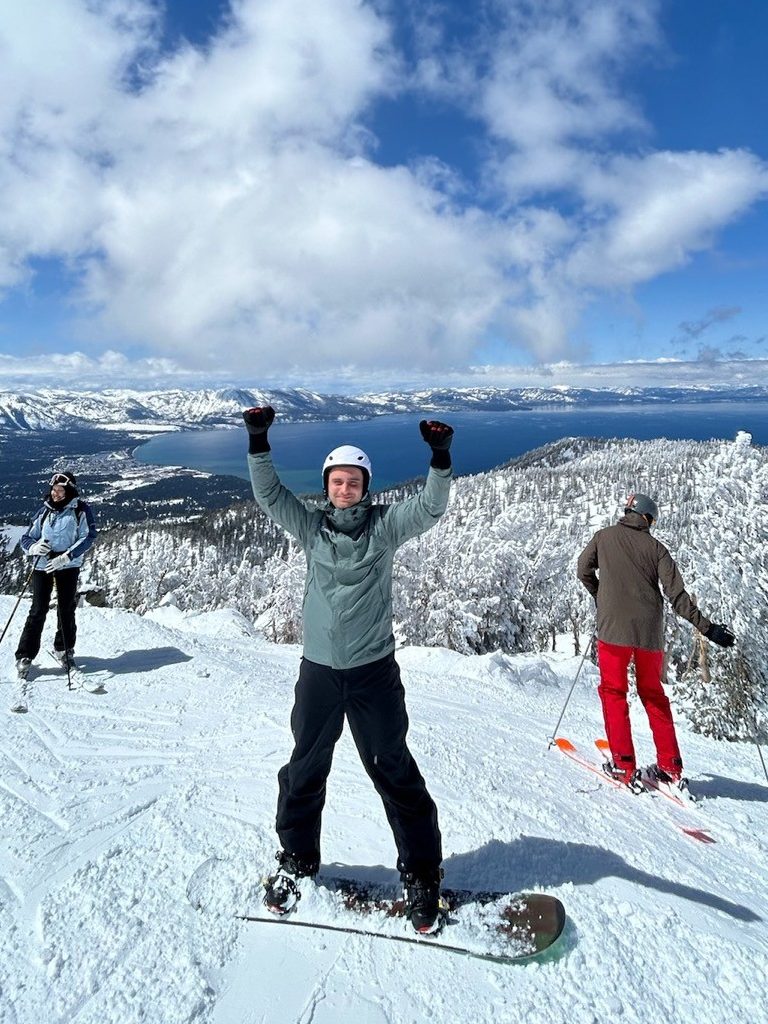 A man standing on a snowboard on a snowy hill.
