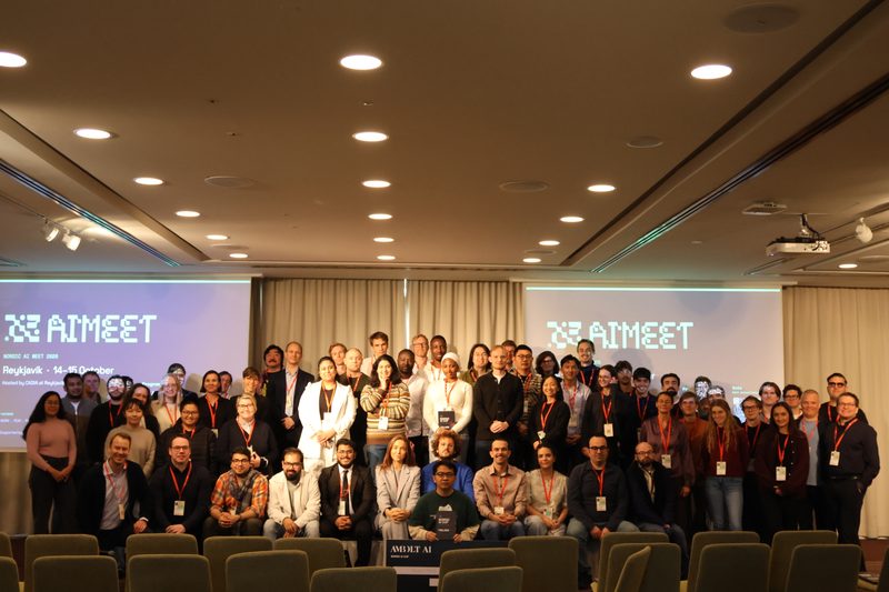 Group photo of a big group in front of screens.