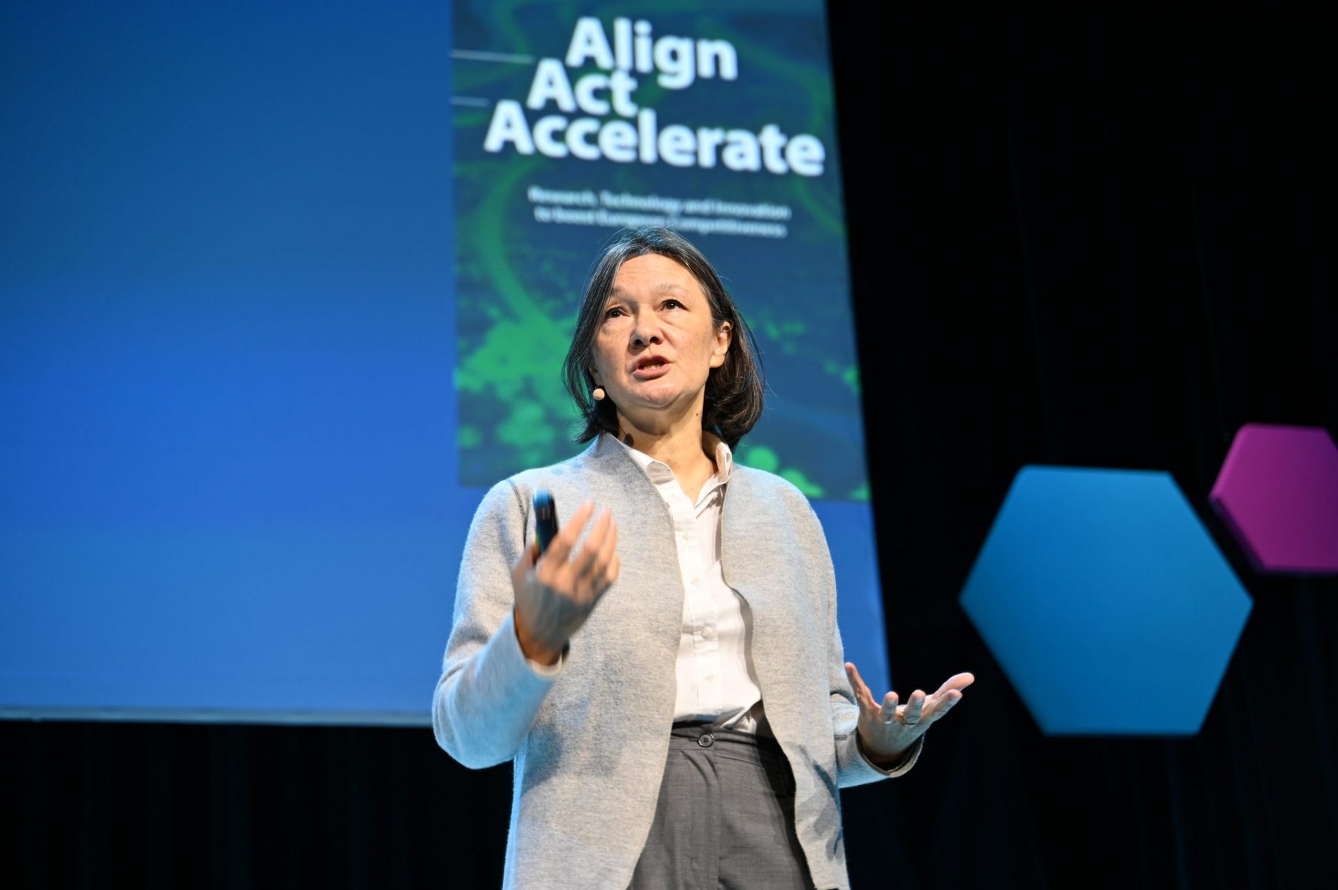 Woman talking on stage with background.