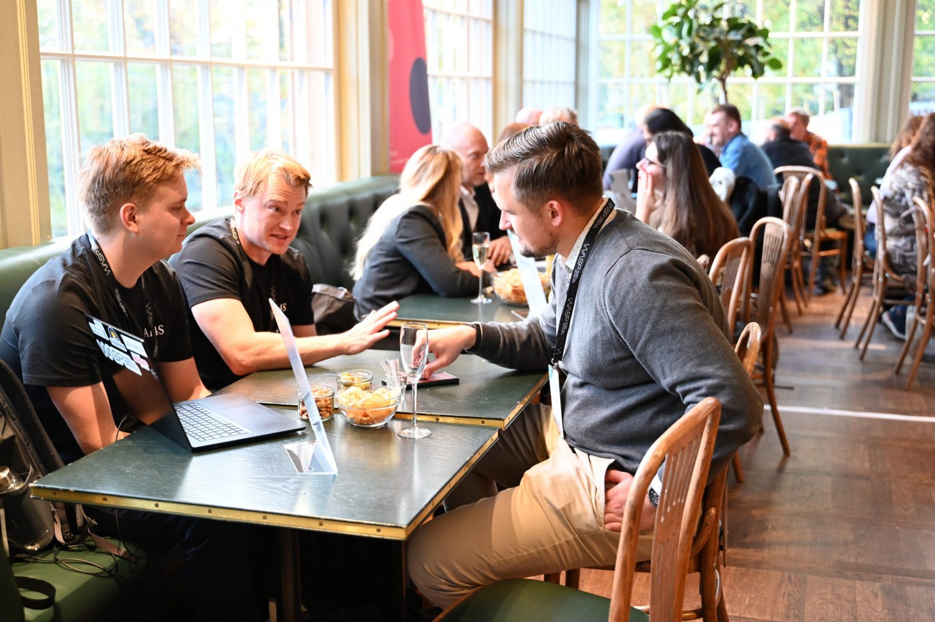 Several people sitting by tables in structured speed networking