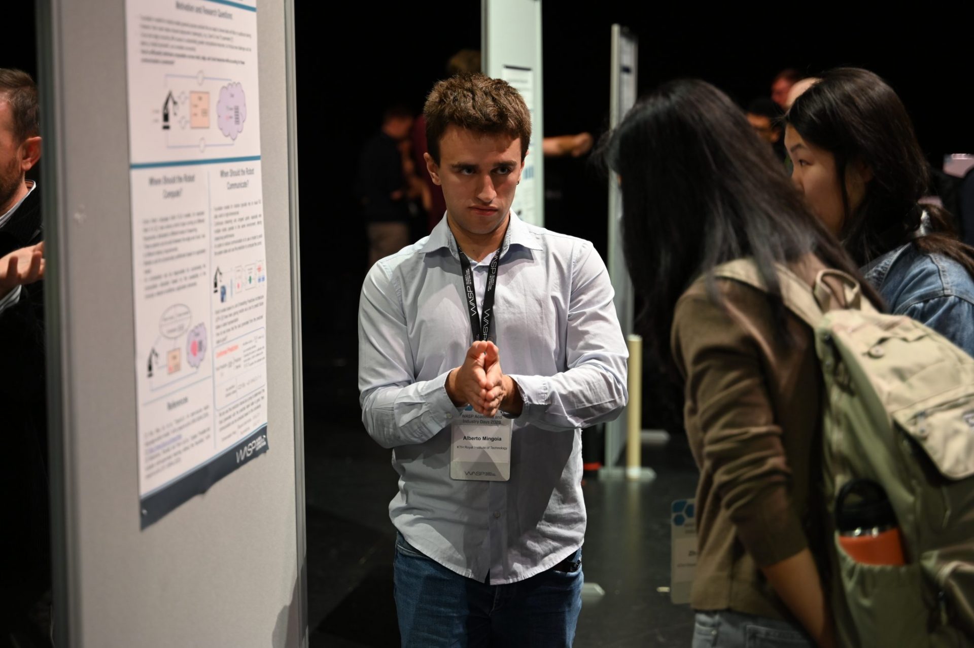 Man talking to two women. at poster session